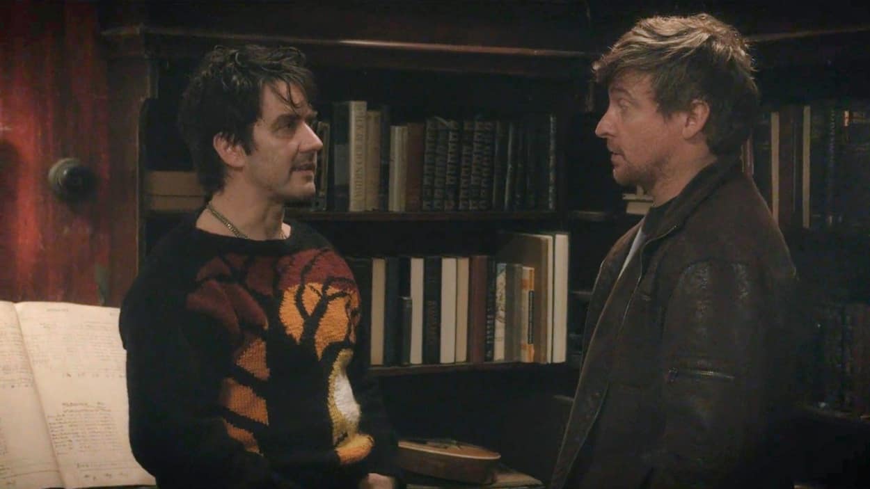Anton and Deacon facing each other in a library from What We Do In the Shadows movie film