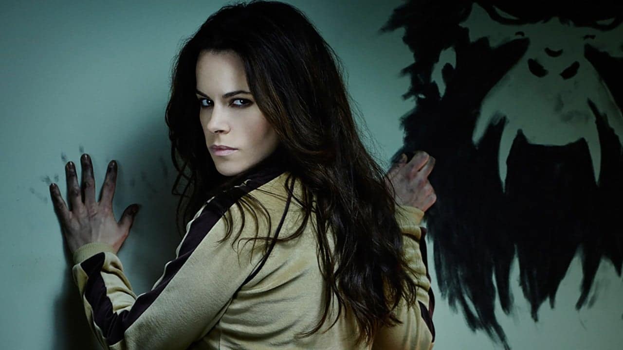 Jennifer goines looking over her shoulder a monkey face on the wall from 12 Monkeys